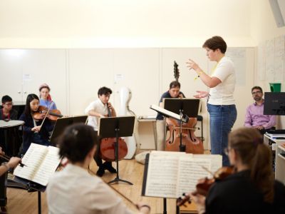 Image of person conducting a string ensemble